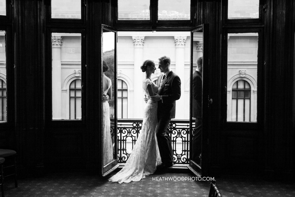 Bride and Groom standing in Fifth Ave window by: Heathwood Photo