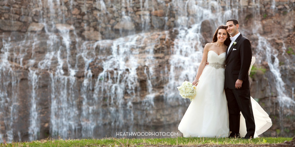 Bride and groom in front of golf course waterfall by: Heathwood Photo