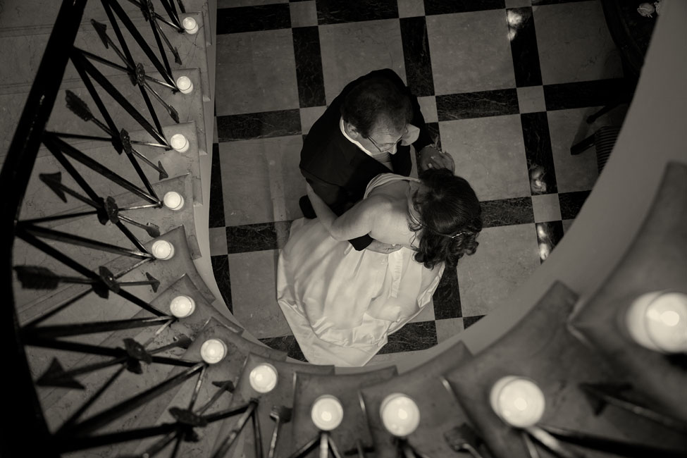Couple share a private moment under lighted staircase by: Robert London Photography